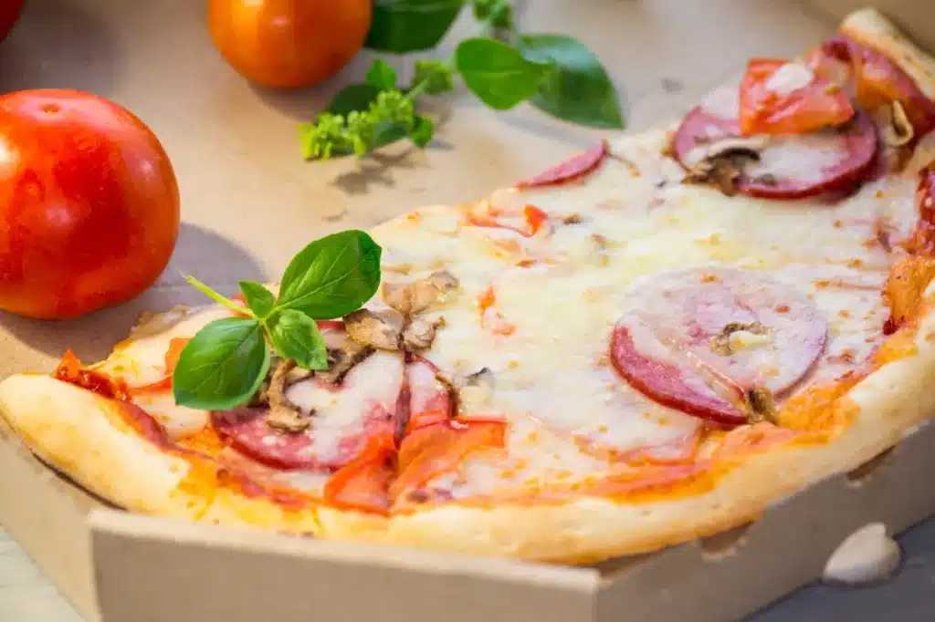 Pizza artisanale fraîchement cuite au feu de bois avec des tomates et du basilic, proposée par un restaurant traditionnel à Saint-Girons.